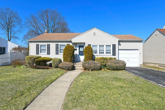 ranch-style house featuring a garage, driveway, a front yard, and fence