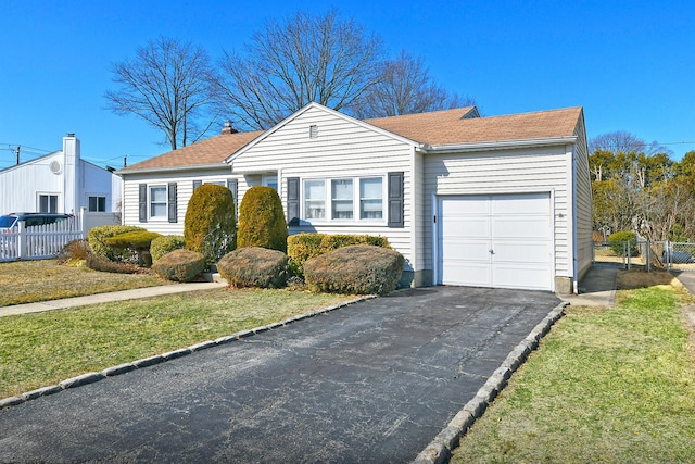 ranch-style house featuring driveway, a front lawn, an attached garage, and fence