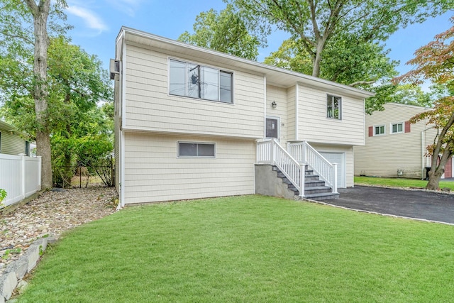 bi-level home featuring aphalt driveway, a front yard, fence, and an attached garage