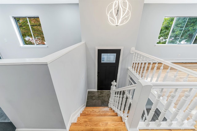 staircase with a notable chandelier, baseboards, and wood finished floors