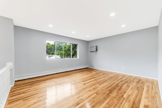 spare room featuring a baseboard heating unit, baseboards, wood finished floors, and recessed lighting