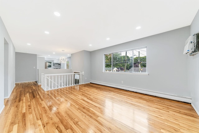 unfurnished room featuring light wood finished floors, a baseboard radiator, baseboards, and recessed lighting