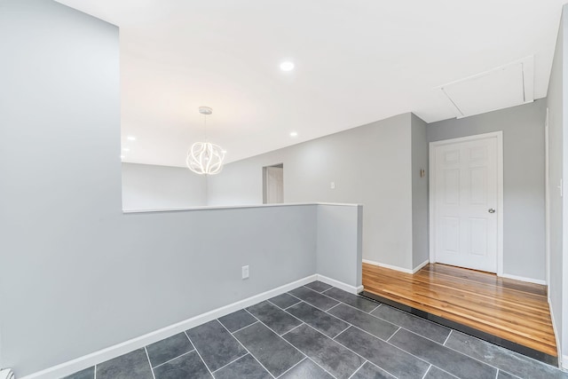 spare room with attic access, baseboards, dark tile patterned flooring, a chandelier, and recessed lighting