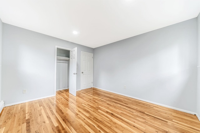 unfurnished bedroom with light wood-type flooring, baseboards, and a closet