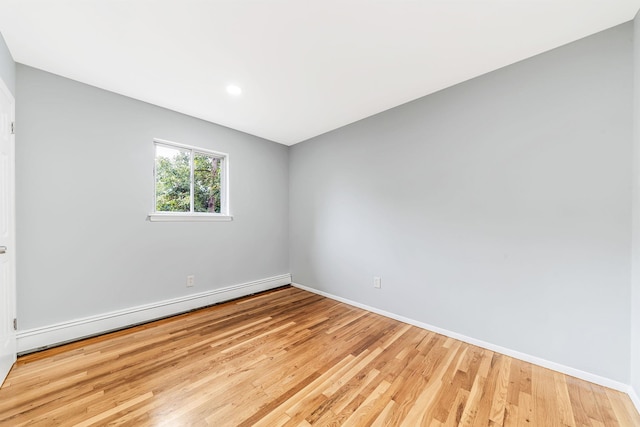 empty room with light wood finished floors, a baseboard radiator, and baseboards