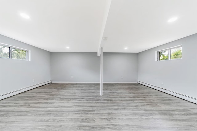 below grade area featuring plenty of natural light, baseboard heating, and wood finished floors