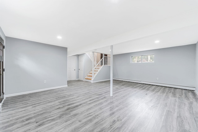 below grade area with a baseboard radiator, recessed lighting, wood finished floors, baseboards, and stairs