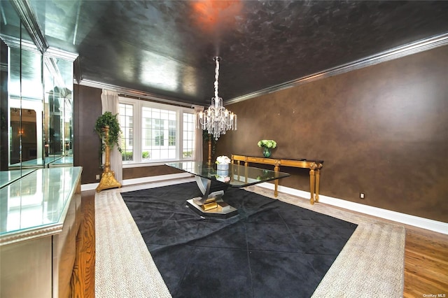 dining space with ornamental molding, a chandelier, baseboards, and wood finished floors