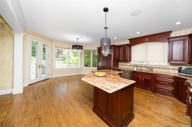 kitchen with light wood-style flooring, decorative backsplash, appliances with stainless steel finishes, a sink, and a kitchen island