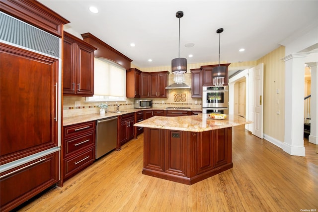 kitchen with light wood finished floors, a kitchen island, appliances with stainless steel finishes, dark brown cabinets, and wall chimney range hood