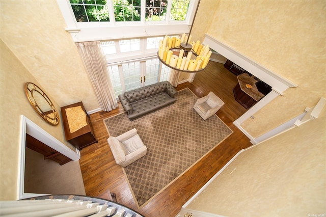 living room featuring a high ceiling, baseboards, and wood finished floors