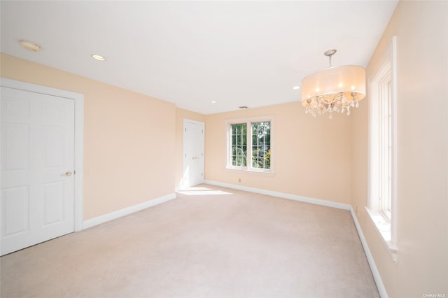 spare room with recessed lighting, baseboards, a notable chandelier, and light colored carpet