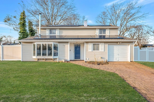 view of front of property featuring solar panels, decorative driveway, a front yard, and fence