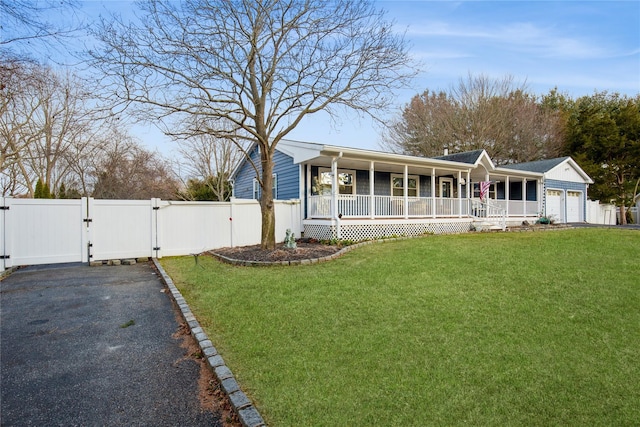 view of front of house with covered porch, a front yard, a gate, fence, and a garage