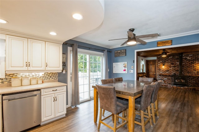 dining area featuring light wood-style floors, recessed lighting, a wood stove, and crown molding