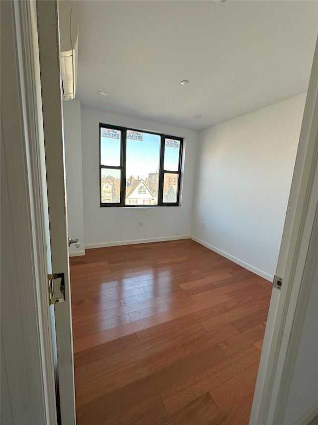 spare room with baseboards and wood-type flooring