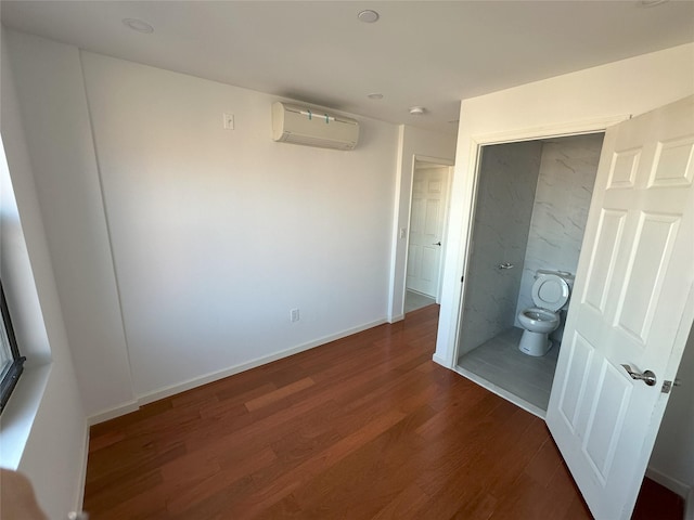 unfurnished bedroom featuring baseboards, an AC wall unit, and wood finished floors