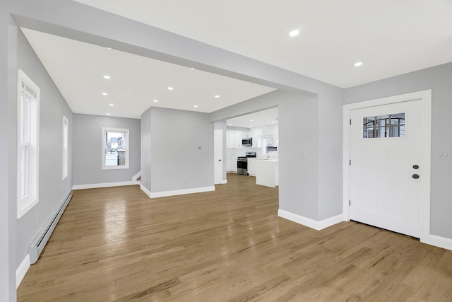 interior space featuring a baseboard heating unit, recessed lighting, light wood-style flooring, and baseboards