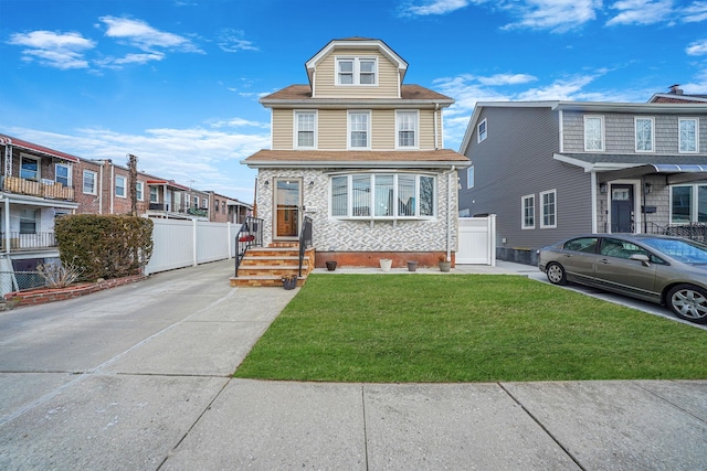 american foursquare style home featuring fence and a front lawn