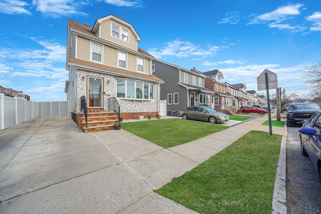 american foursquare style home featuring a residential view, fence, and a front lawn