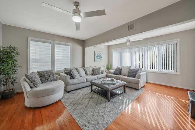 living room featuring light wood-type flooring, visible vents, ceiling fan, and baseboards