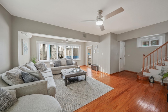 living room featuring light wood-style floors, stairs, and a ceiling fan