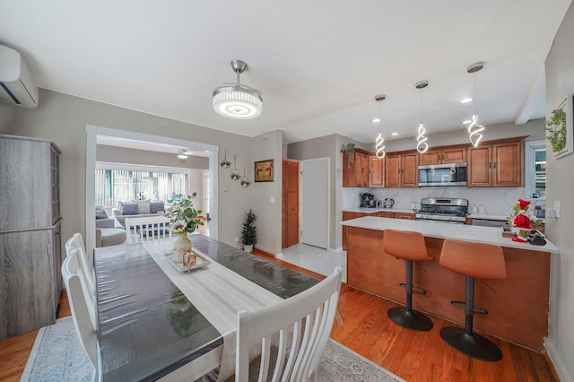 dining area with a wall mounted AC and light wood-type flooring