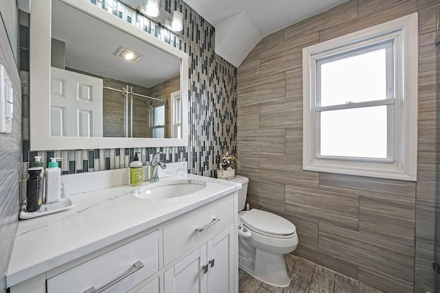 full bathroom with toilet, a stall shower, vanity, and tile walls