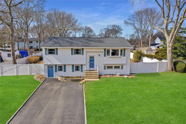 split foyer home featuring driveway, fence private yard, and a front yard