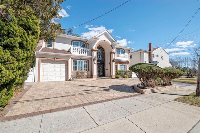 view of front of house featuring a balcony, an attached garage, decorative driveway, and stucco siding