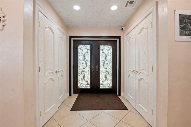 foyer entrance with recessed lighting, french doors, light tile patterned flooring, and visible vents