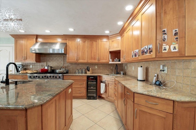 kitchen with light tile patterned floors, wall chimney exhaust hood, wine cooler, stove, and a sink