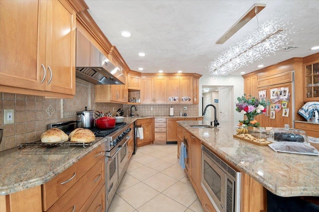 kitchen with light tile patterned floors, tasteful backsplash, built in appliances, a large island with sink, and a sink