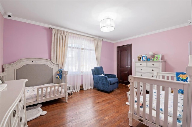 bedroom featuring ornamental molding, a nursery area, and wood finished floors