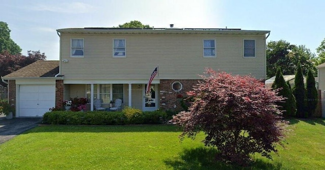 exterior space featuring brick siding, covered porch, a front yard, a garage, and driveway