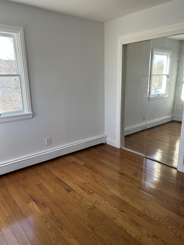 unfurnished bedroom featuring hardwood / wood-style floors, a closet, and a baseboard radiator