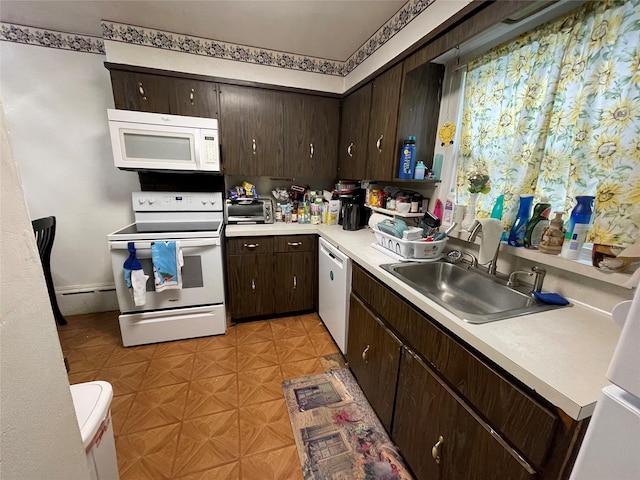 kitchen with dark brown cabinetry, white appliances, light countertops, light floors, and a sink