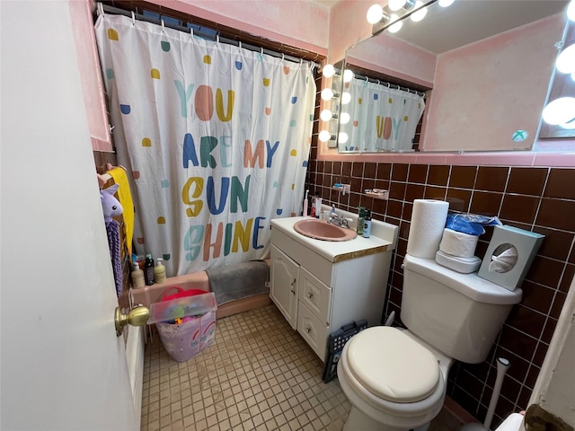 full bath featuring toilet, vanity, tile walls, tile patterned floors, and shower / bath combo