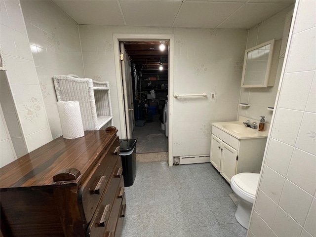 half bath featuring a baseboard heating unit, toilet, vanity, and tile patterned floors