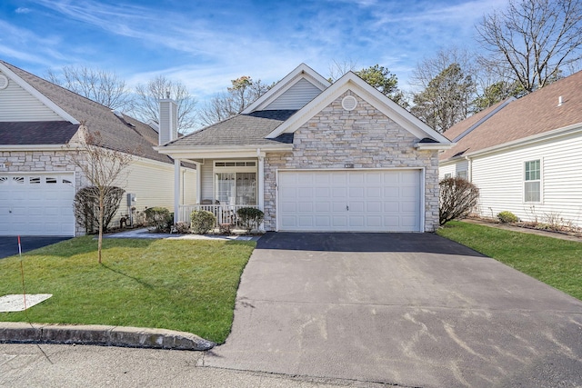 view of front of property featuring aphalt driveway, a chimney, covered porch, a front yard, and a garage