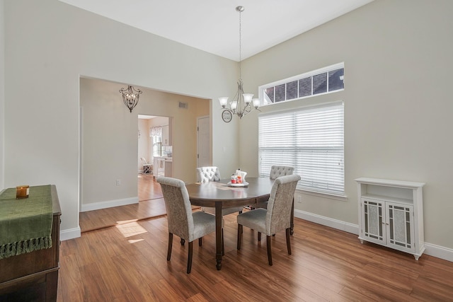 dining room featuring baseboards, visible vents, a chandelier, and wood finished floors