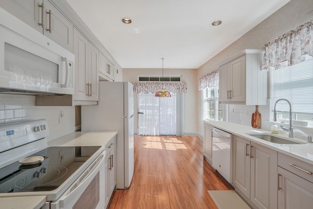 kitchen featuring white appliances, light countertops, a sink, and light wood finished floors