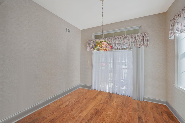 empty room with baseboards, visible vents, and wood finished floors