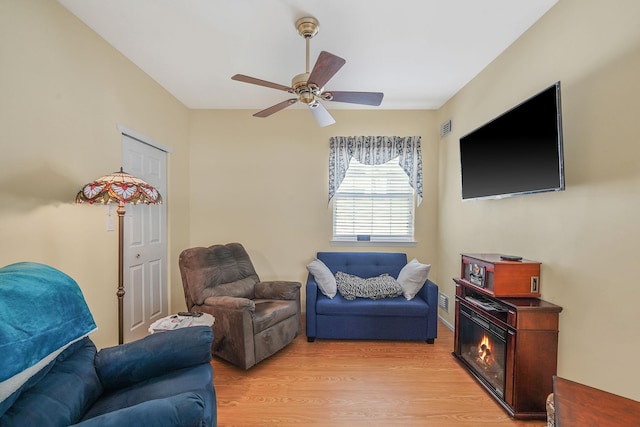 living area featuring light wood-style floors, visible vents, and a ceiling fan