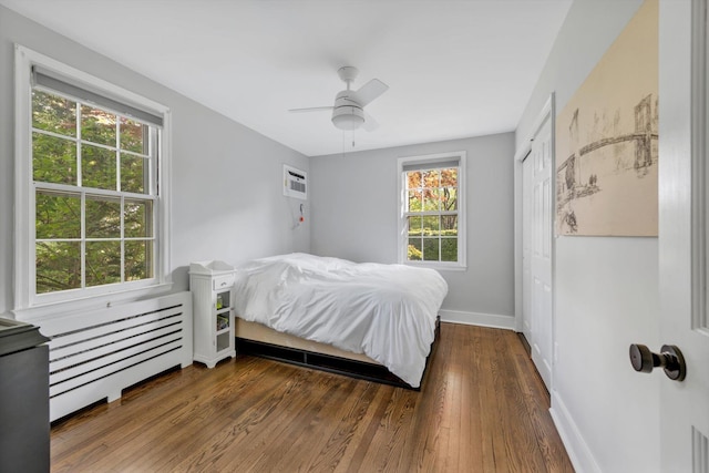 bedroom featuring radiator, a closet, baseboards, and wood finished floors