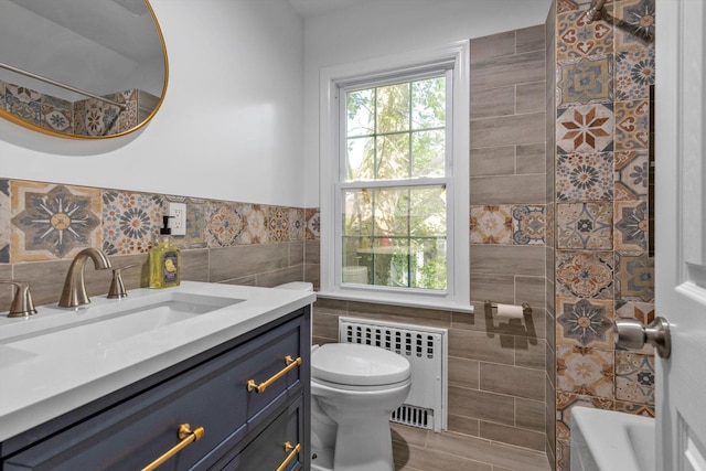 full bathroom with toilet, a healthy amount of sunlight, tile walls, and radiator