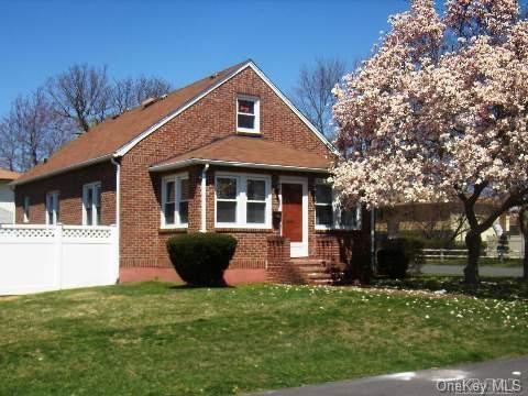 view of front of property featuring a front lawn, fence, and brick siding