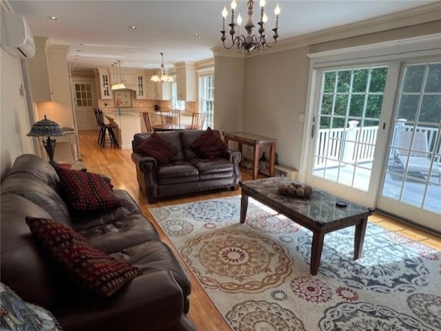 living area with ornamental molding, a wall mounted air conditioner, light wood-style flooring, and a notable chandelier