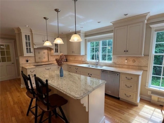 kitchen featuring dishwasher, a center island, black electric stovetop, a kitchen bar, and a sink