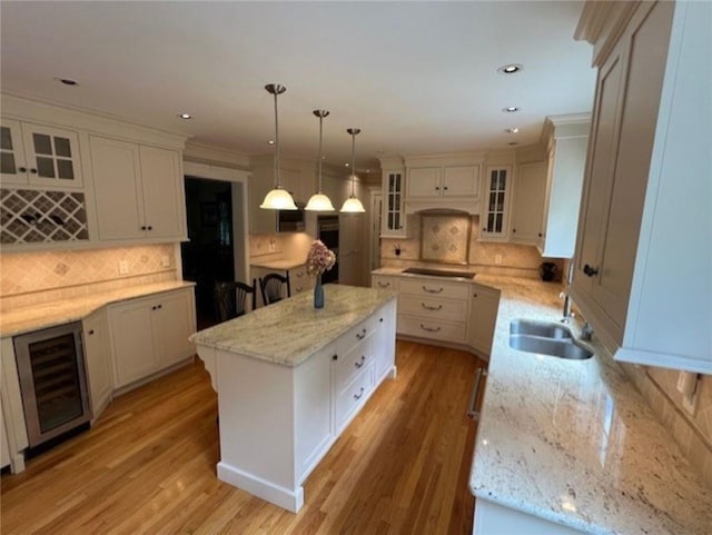 kitchen featuring wine cooler, a center island, a sink, light wood-type flooring, and stovetop